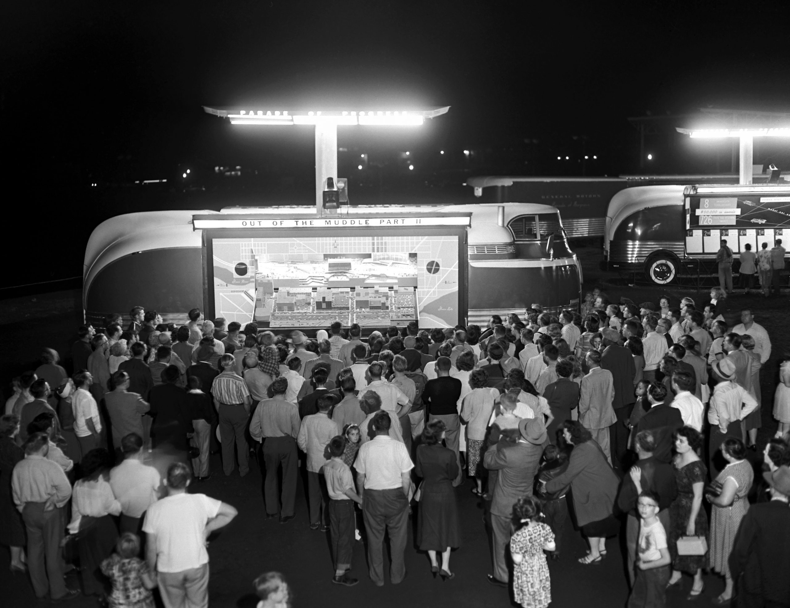 night scene of a Futurliner with light tower deployed and people crowded around the stage