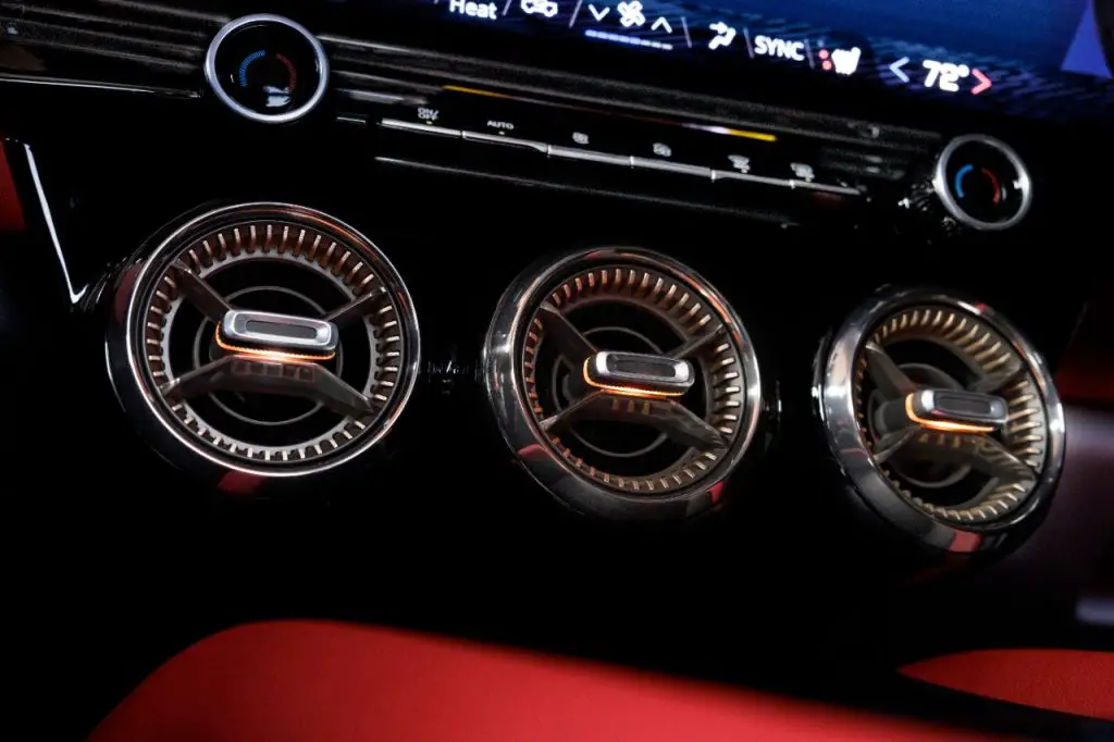 Close up of round air vents in tech bronze inside the 2024 Chevrolet Blazer EV SS in Radiant Red Tintcoat with Adrenaline Red interior. Preproduction model shown. Actual production model may vary. 2024 Chevrolet Blazer EV available Spring 2023.