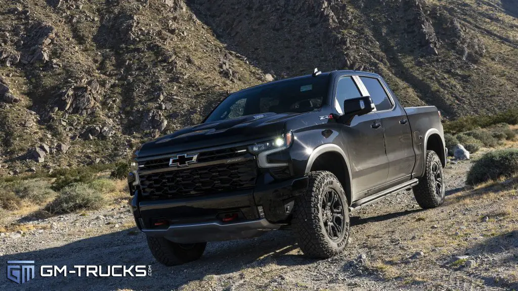 A 2024 Chevrolet Silverado 1500 ZR2 in a sandy desert with a rocky mountain behind it