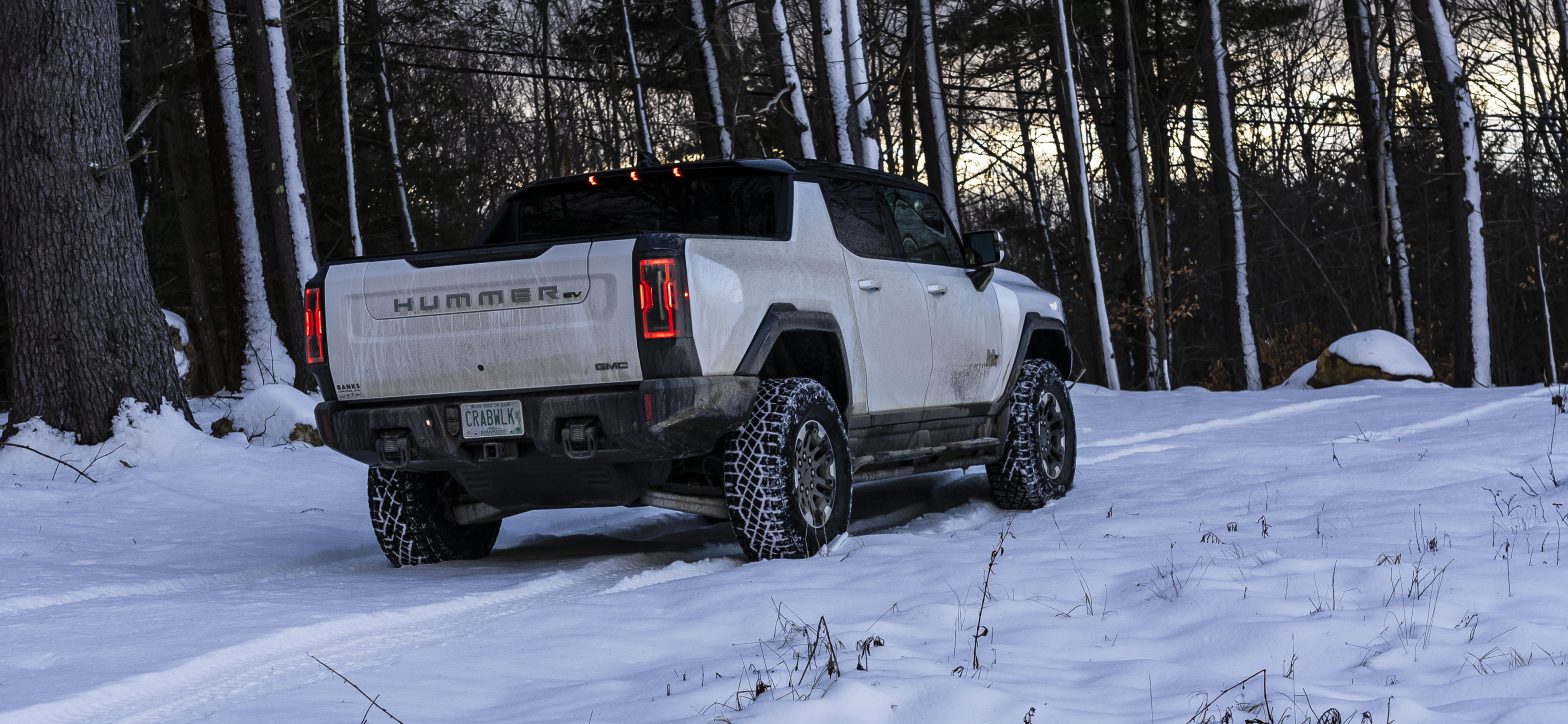 A HUMMER EV Pickup in a snowy scene with trees in the background