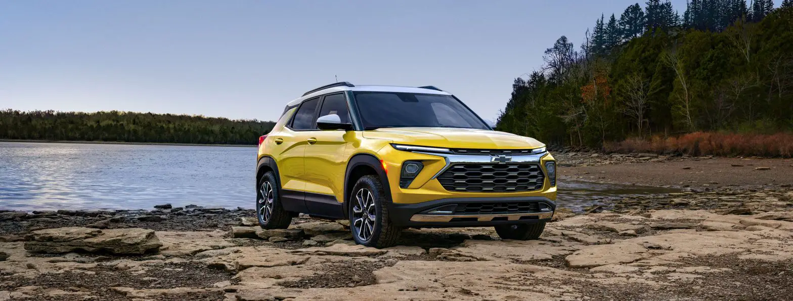 Front 3/4 view of 2025 Chevrolet Trailblazer ACTIV in Nitro Yellow Metallic parked on a rock bank in front of a lake.