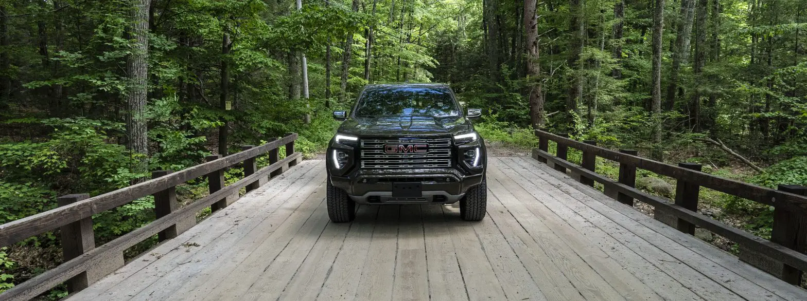 A GMC Canyon Denali from a front view- sitting still on a wooden bridge