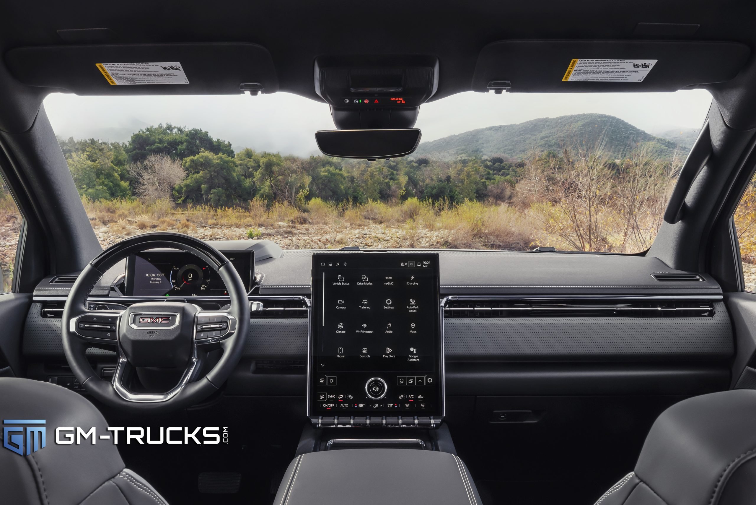 Still Don’t Trust EV Trucks? The 2026 GMC Sierra EV Is Built to Change That With A Lower Price & More Trims 7 Driver’s view of the 2026 GMC Sierra EV interior showing a digital instrument cluster, large vertical touchscreen, and modern dashboard with a view of the outdoors through the windshield.