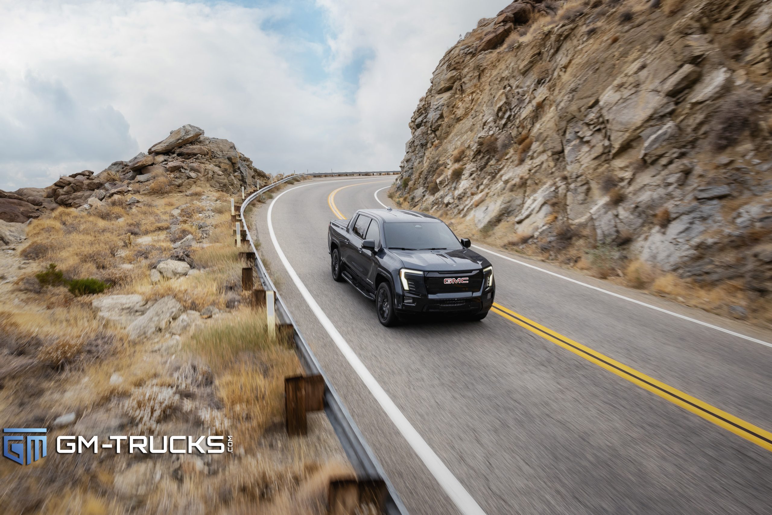Still Don’t Trust EV Trucks? The 2026 GMC Sierra EV Is Built to Change That With A Lower Price & More Trims 4 A black 2026 GMC Sierra EV Elevation driving through a winding mountain road, showcasing its standard 18-inch wheels and everyday road usability.