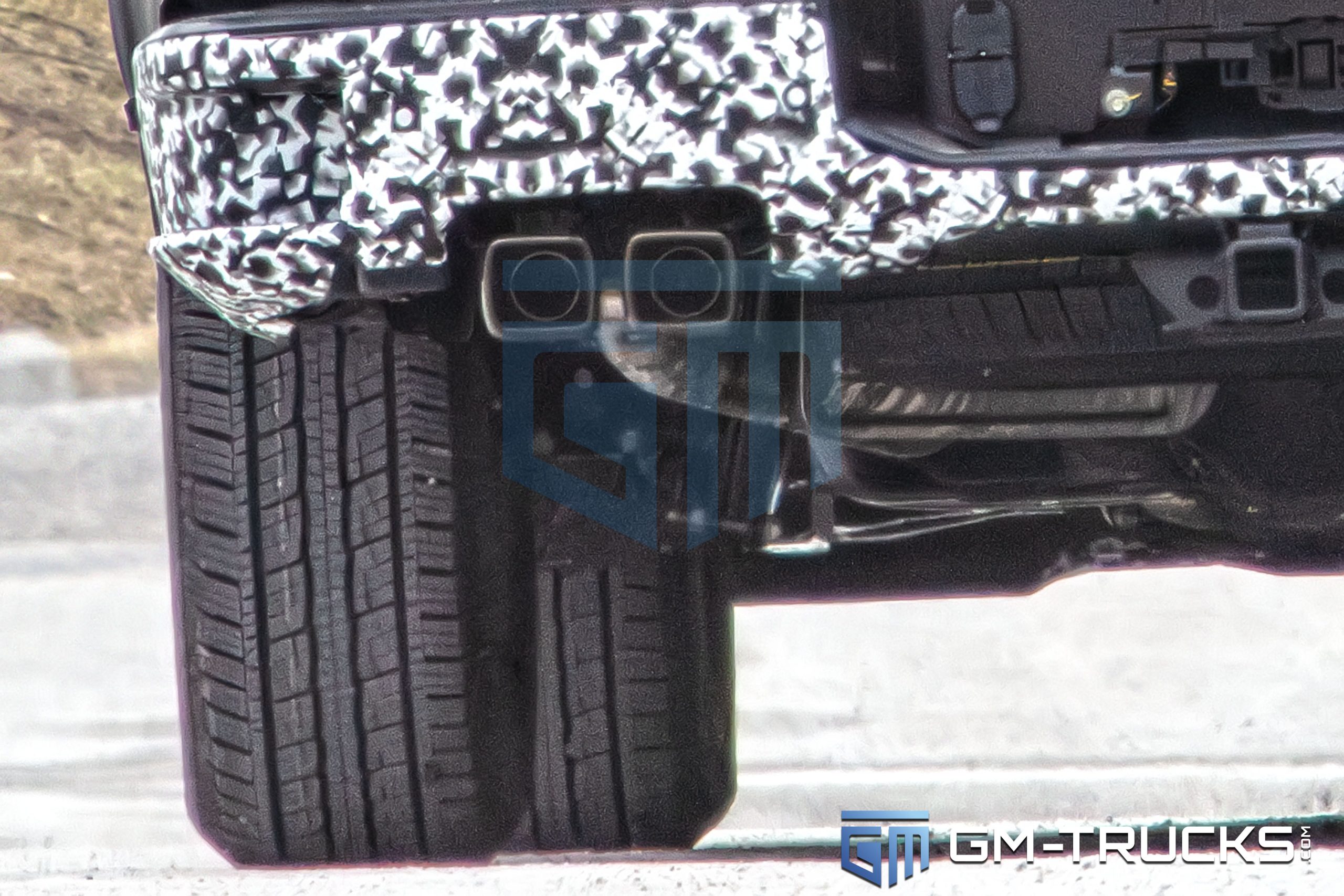 2027 Chevy Silverado Spied with Quad Exhaust, Off-Road Upgrades & High-Tech Interior 8 Close-up of the 2027 Chevrolet Silverado prototype’s rear suspension, showing quad-tip exhaust, revised shock placement, and underbody details.