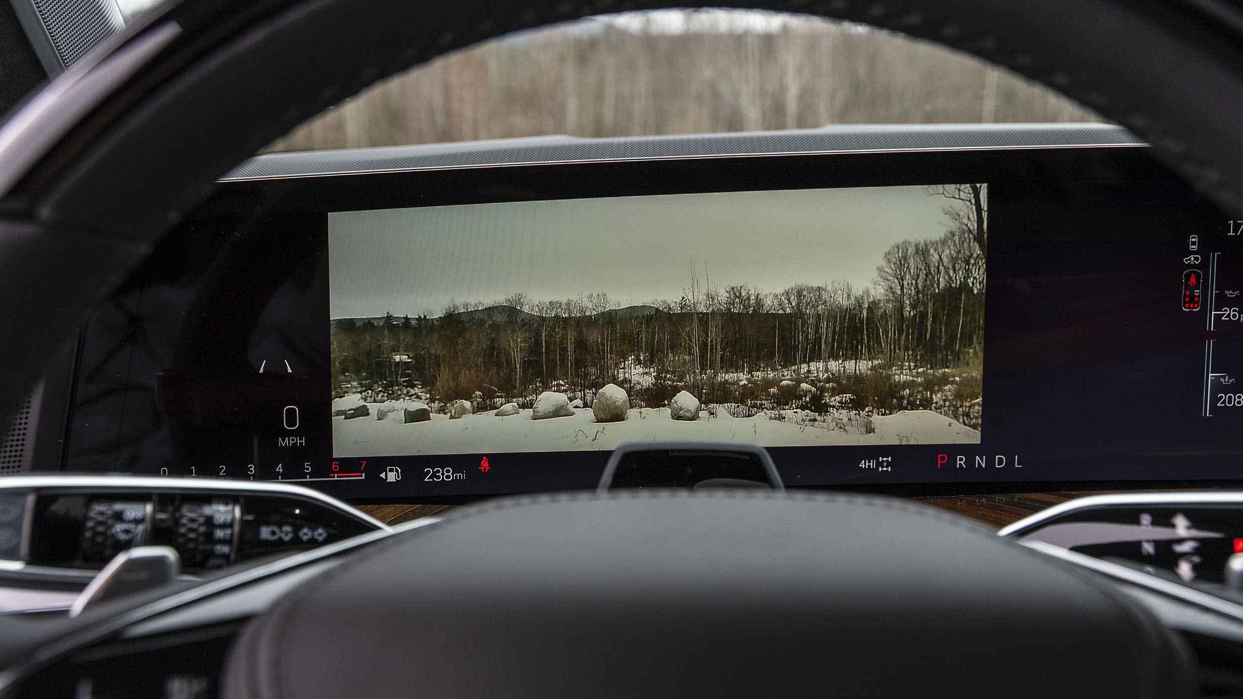Power Open Doors, Night Vision & 55-Inch Displays: 5 Wild Tech Features on the 2026 Escalade 5 A view through the steering wheel of the 2026 Cadillac Escalade's digital gauge cluster showing a live, high-definition front camera feed of a snowy field and trees.