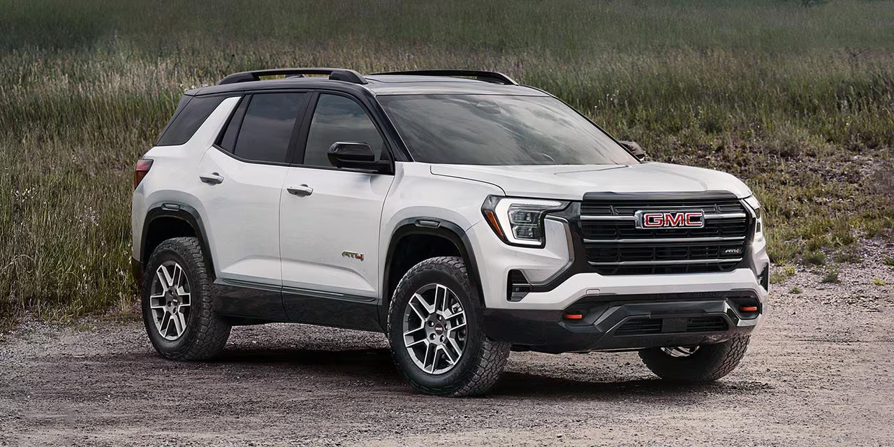 2027 GMC Terrain Drops the CVT and Adds Tesla-Like Connected Dash Cams 4 Front three-quarter view of a white next-generation GMC Terrain AT4 parked on a dirt road, featuring a black two-tone roof, black front grille, red front recovery hooks, and chunky all-terrain tires.