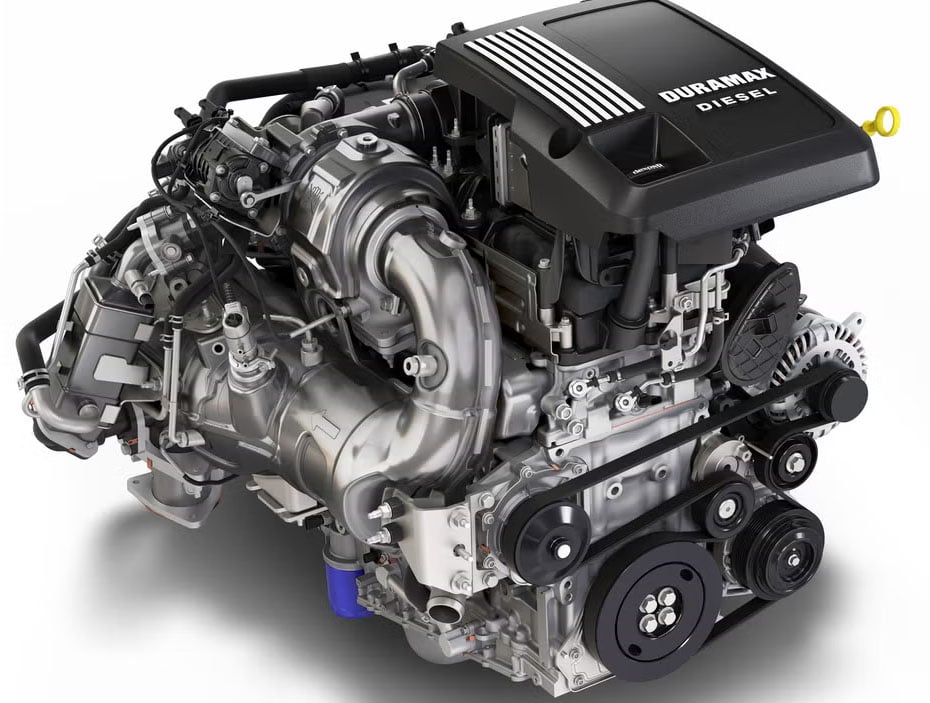 2027 Chevy Silverado Dealer Leaks: 5.7L V8 & 1,000-Mile Range Rumors 4 A studio photograph of the current General Motors 3.0L Duramax inline-six turbodiesel engine, highlighting the black Duramax engine cover, aluminum piping, and front accessory drive pulleys.