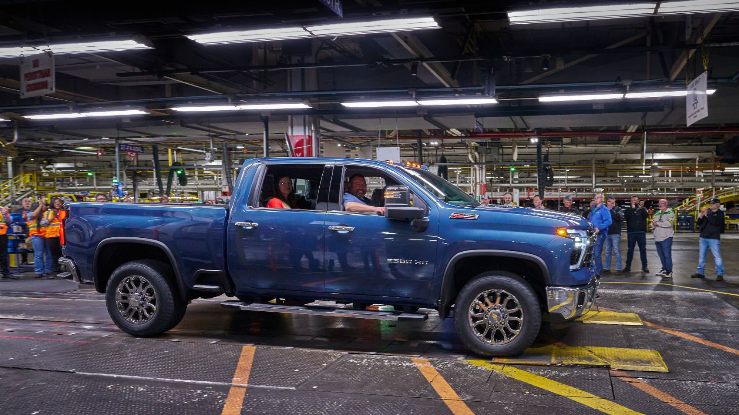 American Made: 27 Million Trucks Built at Fort Wayne and Flint 2 A Lakeshore Blue Metallic Chevrolet Silverado 2500 HD LTZ is shown moving along the final test stand and dynamometer within the GM Flint Assembly factory, with workers observing from the background.