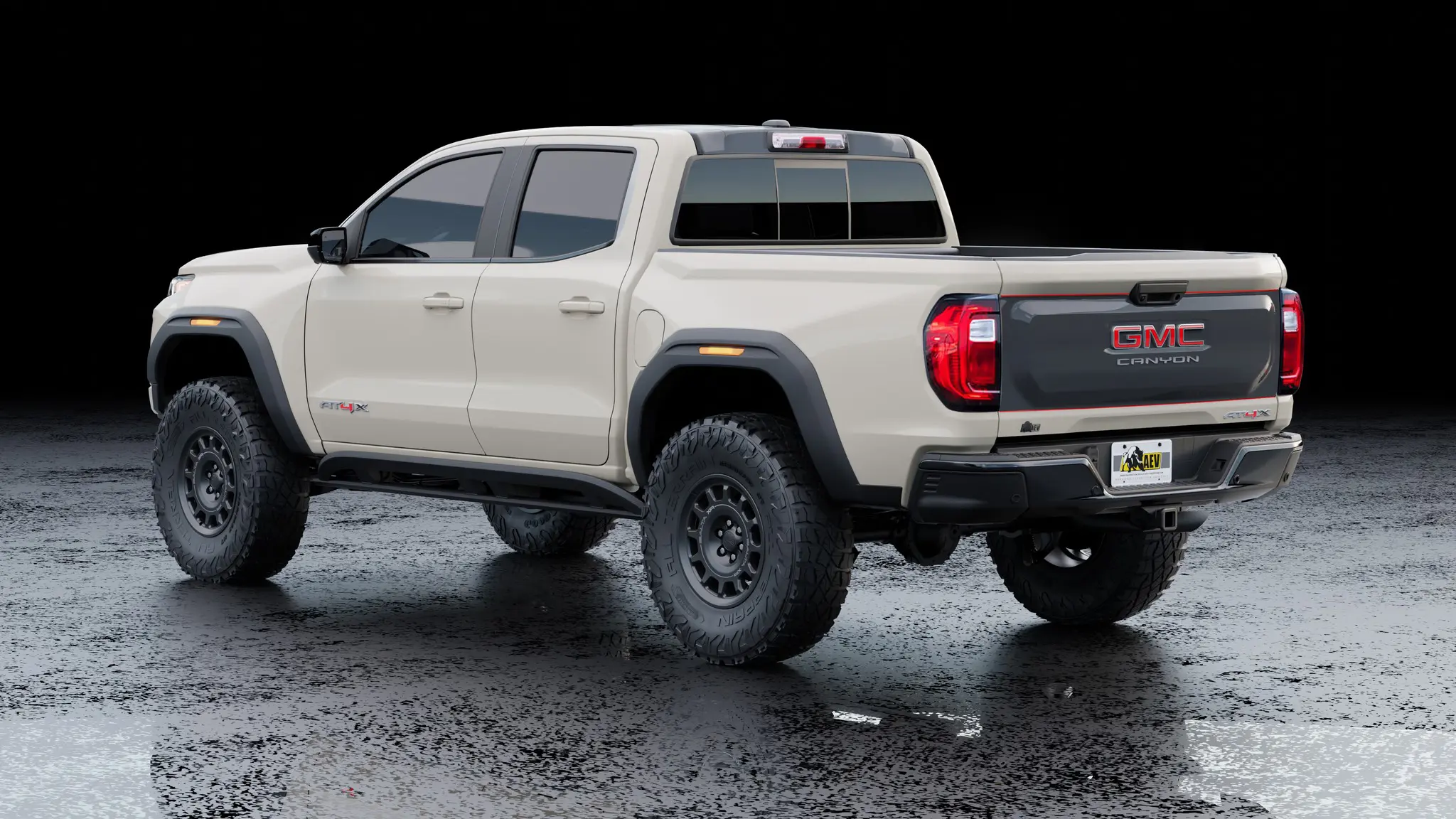 AEV’s Warranty-Backed Conversions Turn Your Colorado ZR2 / Canyon AT4X Into a 35-Inch Tire Off-Road Beast 5 Rear three-quarter view of a light tan GMC Canyon AT4X equipped with the AEV 35-inch tire turn-key conversion package, showing AEV Salta XR wheels, HighMark flares, and custom tailgate graphics.