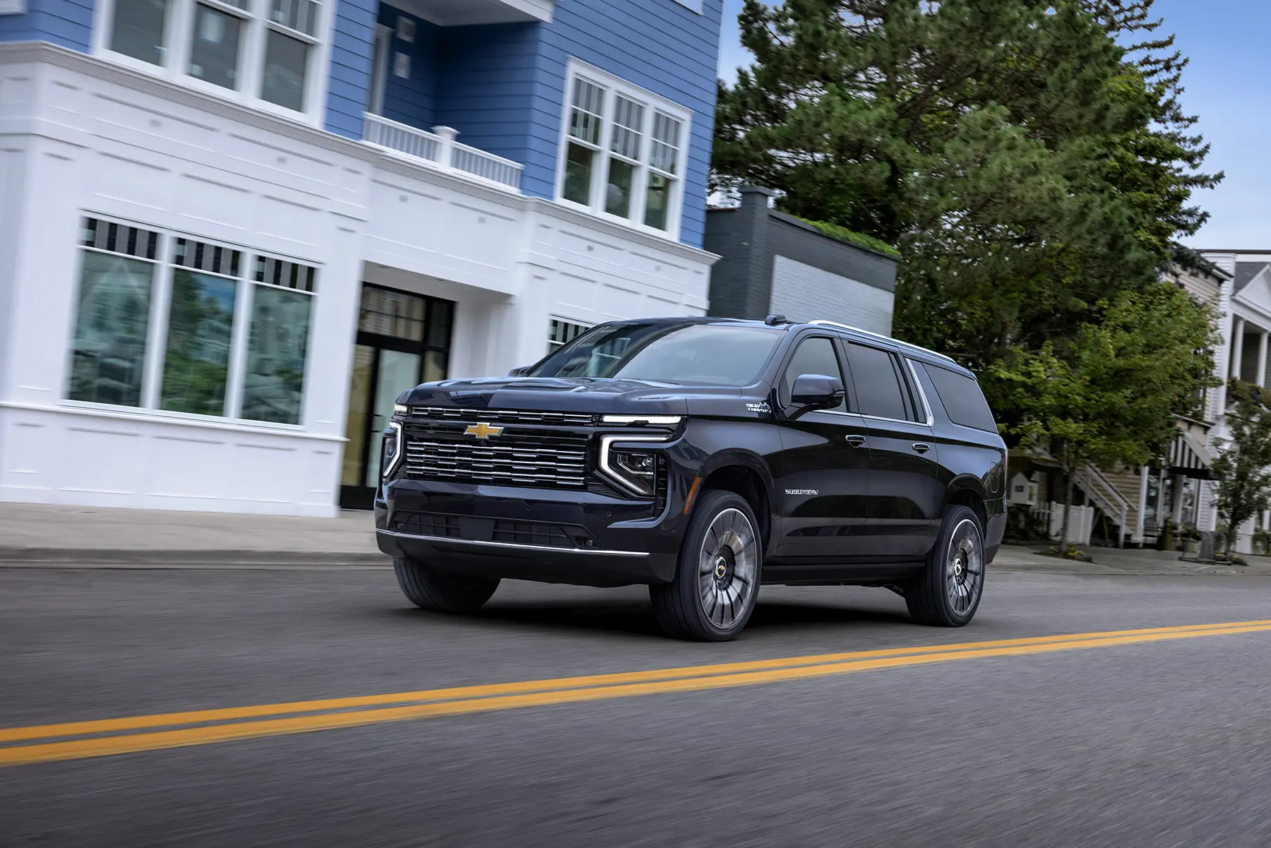 URGENT DO NOT DRIVE: GM Recalls Silverado, Sierra, and SUVs Over Wheel Lockup 2 A dark blue 2026 Chevrolet Suburban High Country driving down a city street, representing one of the primary SUV models affected by General Motors' recent transfer case and wheel lockup safety recall.