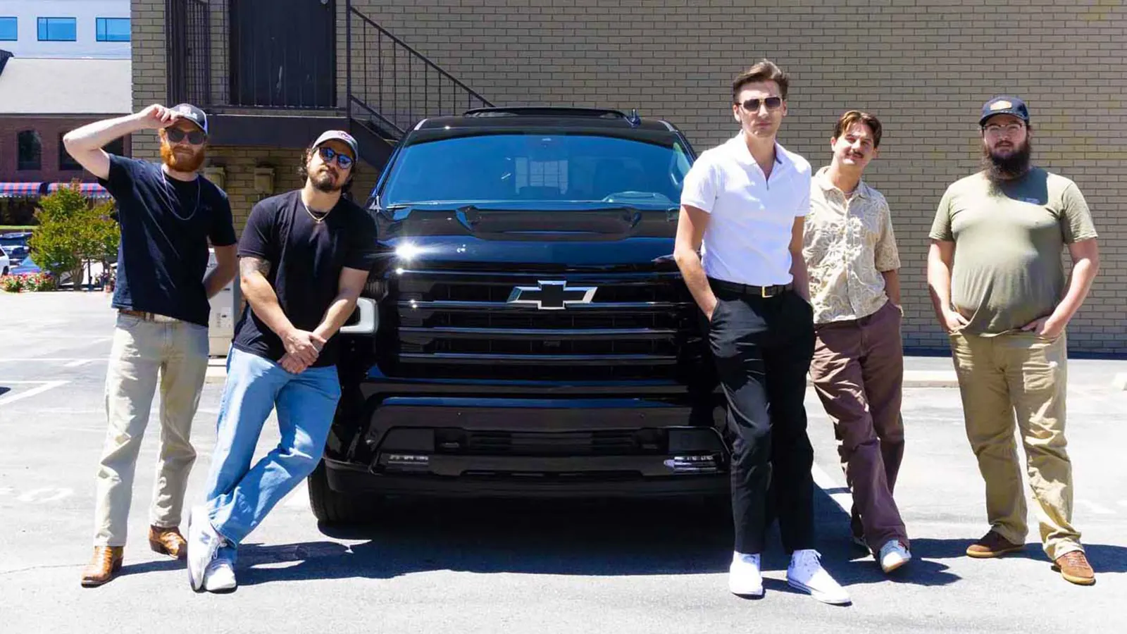Chevy Revives Iconic “Heartbeat of America” Campaign 2 The five members of the rock band The Red Clay Strays pose together in a sunny parking lot while leaning against a black Chevrolet Silverado pickup truck.