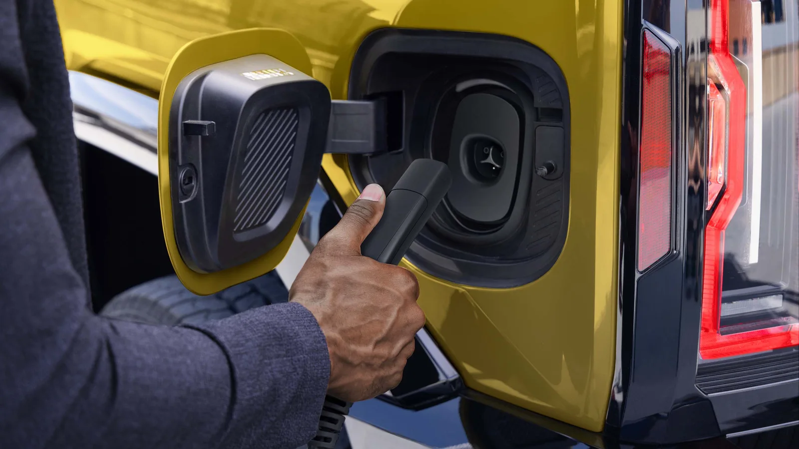 Hummer Turns 25 and GMC Brought the H2's Yellow Back 4 Close-up of the native NACS charging inlet on a yellow 2027 GMC HUMMER EV as a driver prepares to plug in