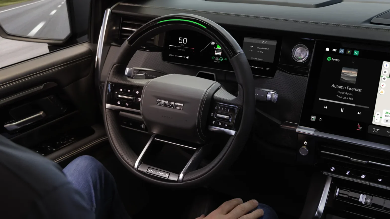 Super Cruise engaged in a 2027 GMC Sierra 1500 Denali Ultimate, with the green light bar illuminated on the steering wheel and the driver's hand off the rim